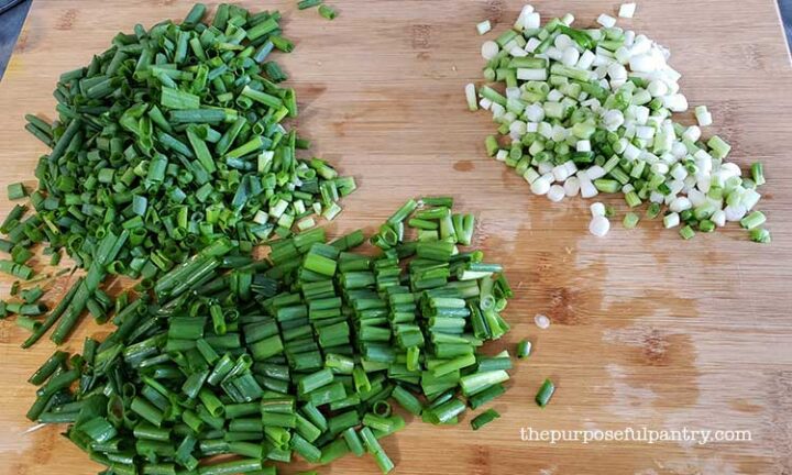 groene uien of lente-uitjes gehakt op een houten snijplank