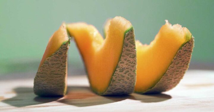 Geschnittene Moschusmelone auf einer Tischplatte mit blauem Hintergrund