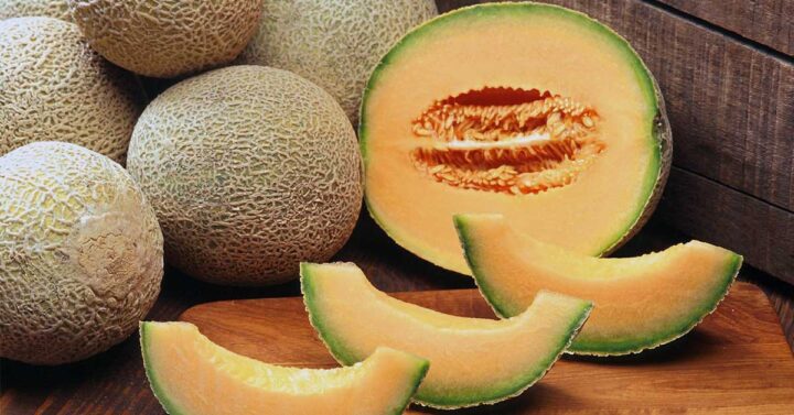  Cantaloups entiers, coupés en deux et tranchés sur fond bois.